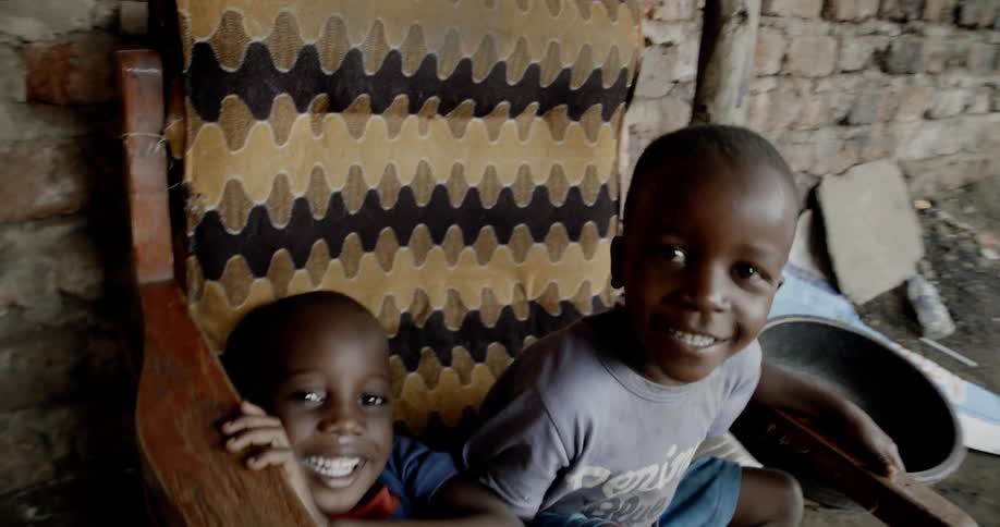 A pair of boys smiling while sharing a wooden chair