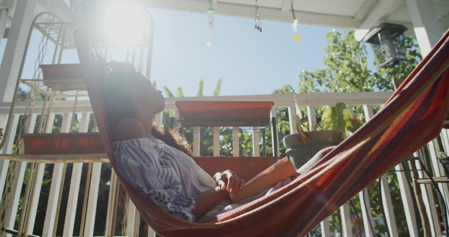 A woman laying on a hammock in the sunshine