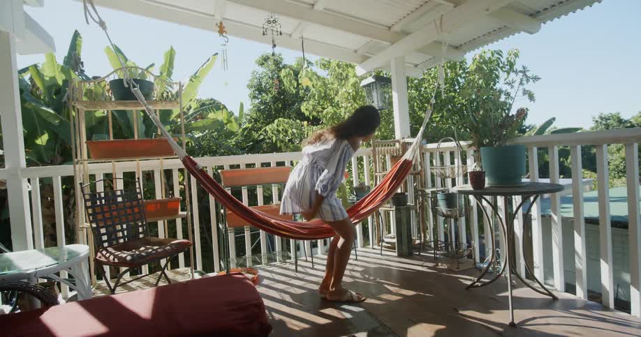 A girl lays in a hammock on a porch