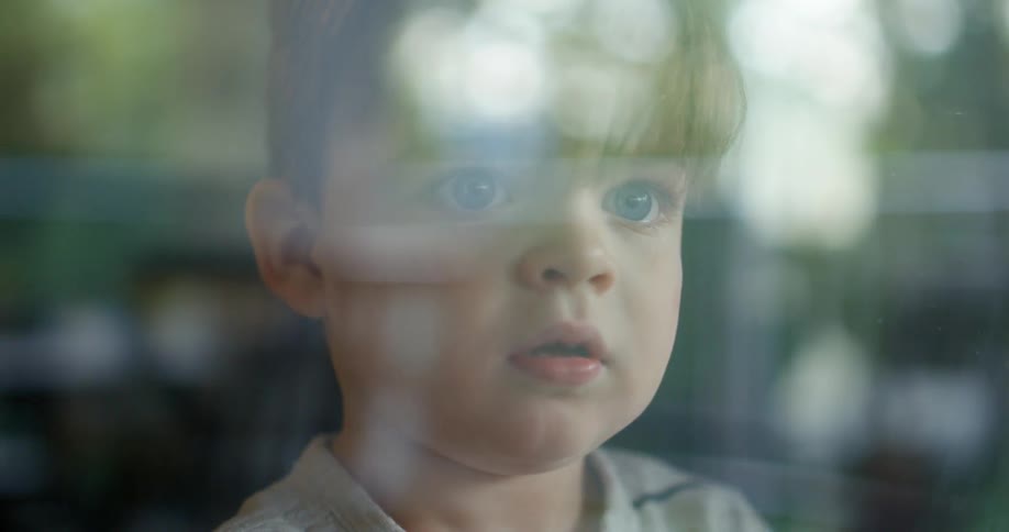 A baby boy looking out of a window