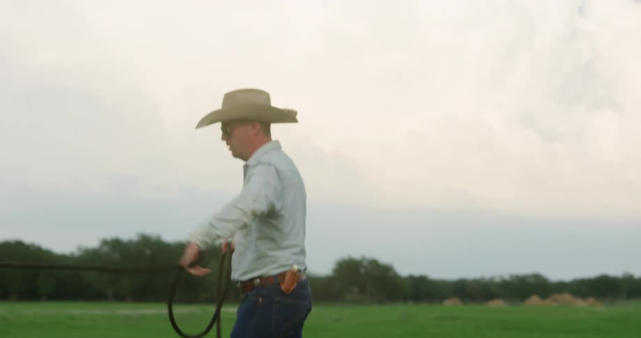 A horse walks in circles around a cowboy on a ranch
