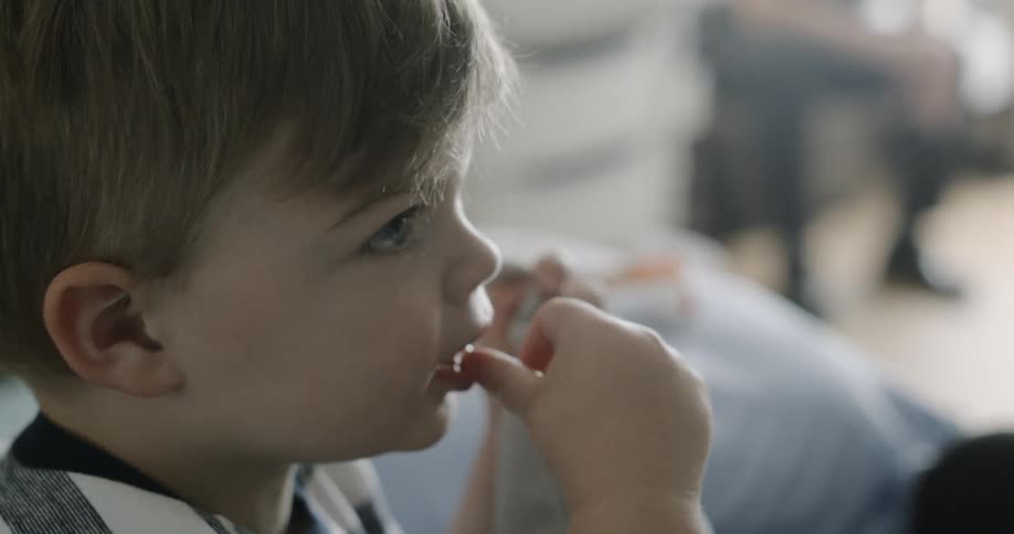 A toddler boy sucks his thumb while holding a blanket