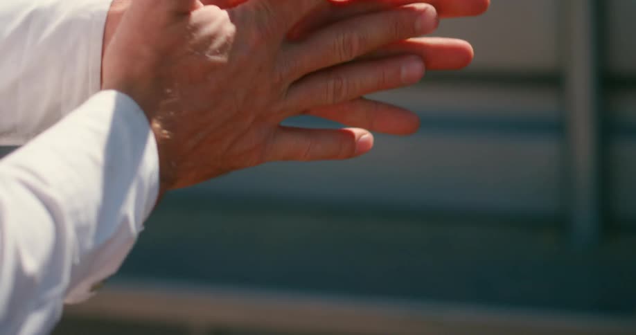 A man rubs his hands together and rubs his thumb against his finger as if it is sticky