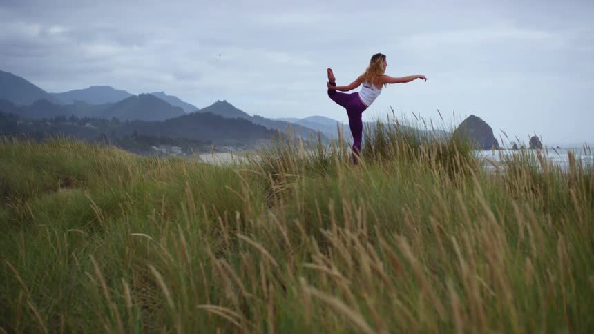Woman performs yoga on the grass on a cloudy day