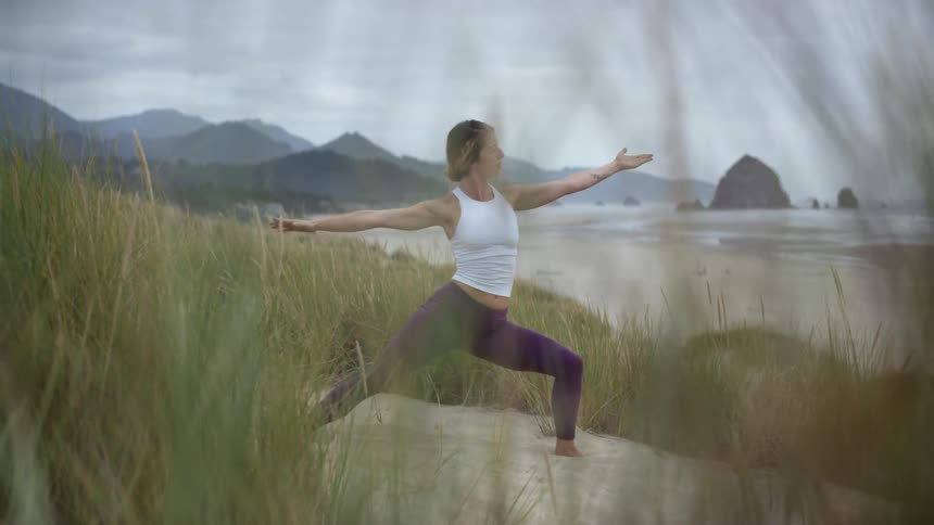 A woman bends backward while doing yoga on the beach