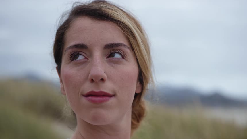 A woman smiles while looking around on a hill