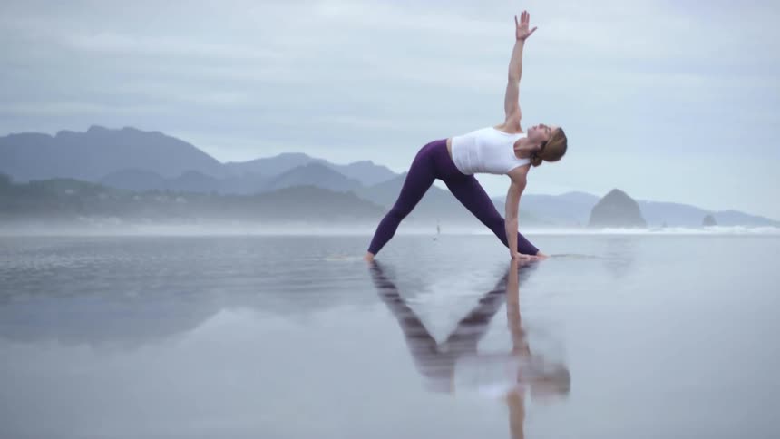 A woman doing yoga on a wet beach