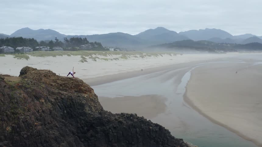 Woman doing yoga on a plateau on a cliff near a sand dune