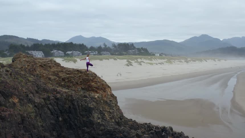 A woman does yoga on a rock