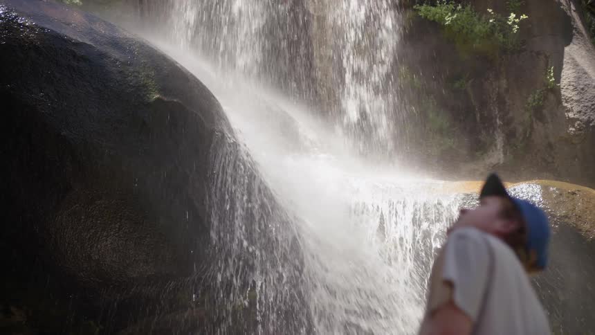A man is looking up at a waterfall