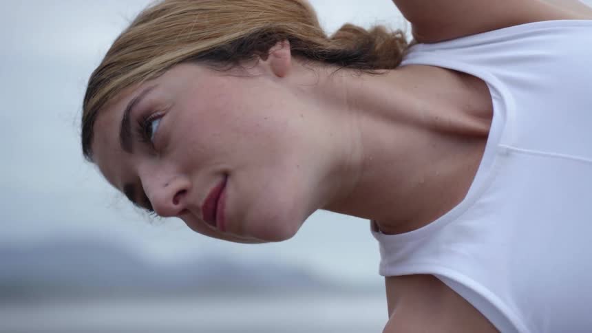 A woman subtly smiles as she stretches while practicing a yoga pose