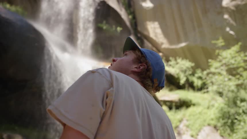 A man looking up at a waterfall