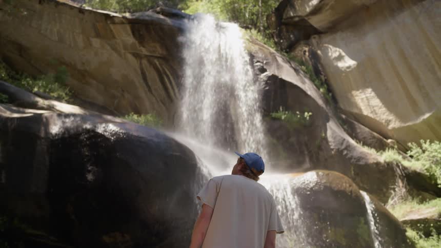 A man looking up at a small waterfall