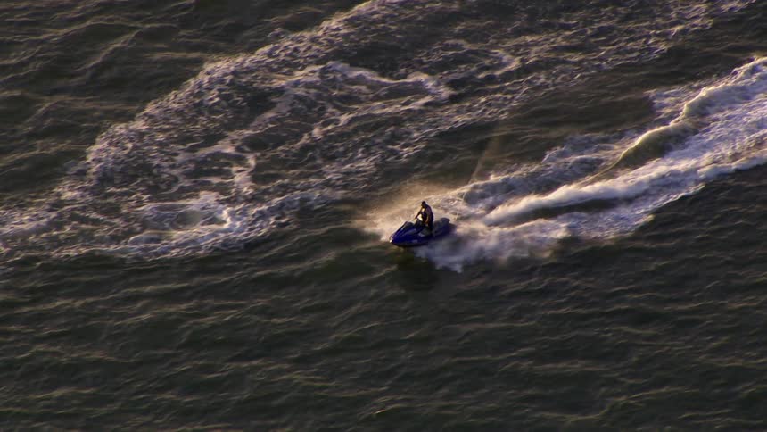 Someone riding a blue jet ski and meeting up with another rider on a green jet ski