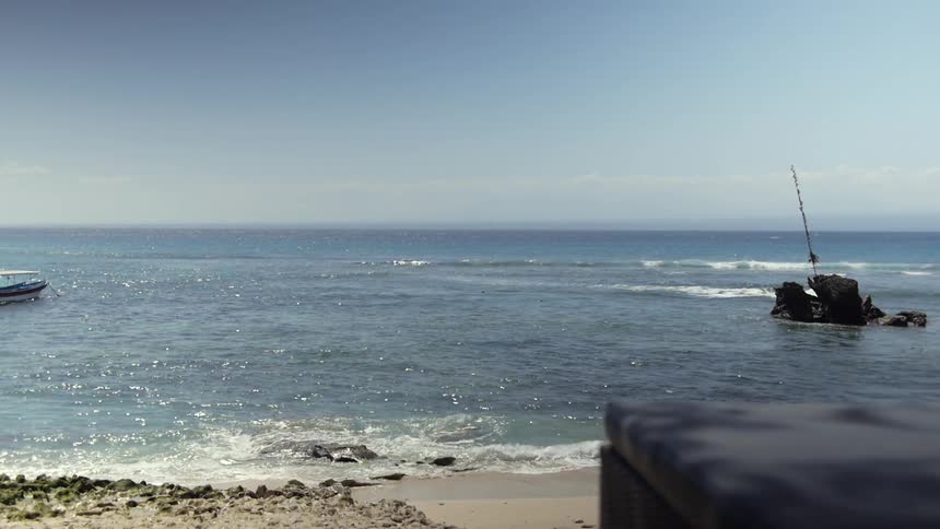 An elevated view of a small beach with small waves landing on the shore