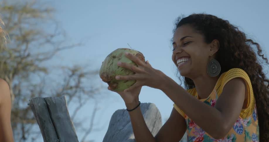A young girl drinks out of a coconut
