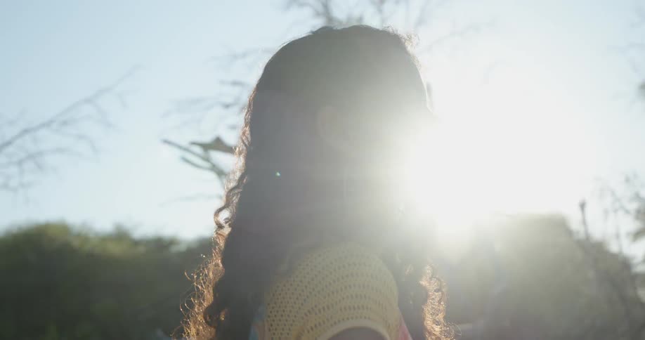 A woman standing outside with trees and the sky in the background