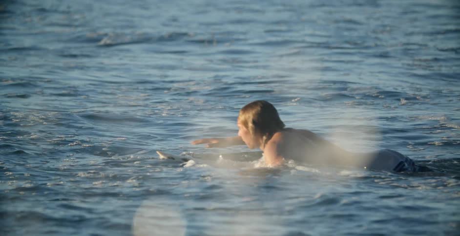 A man swims atop his board
