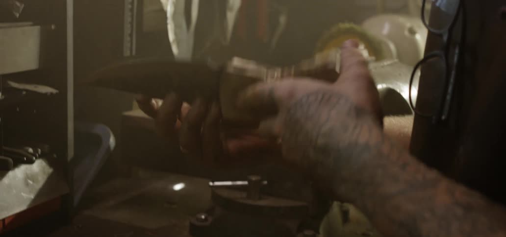 White man checks the knife that he has sharpened at sunset in the workplace