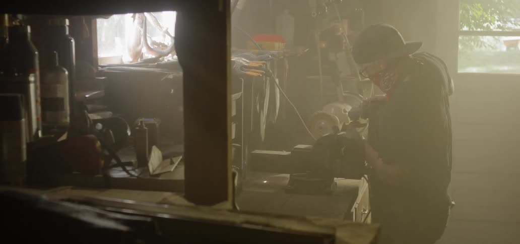 A man uses a sanding power tool in a workshop