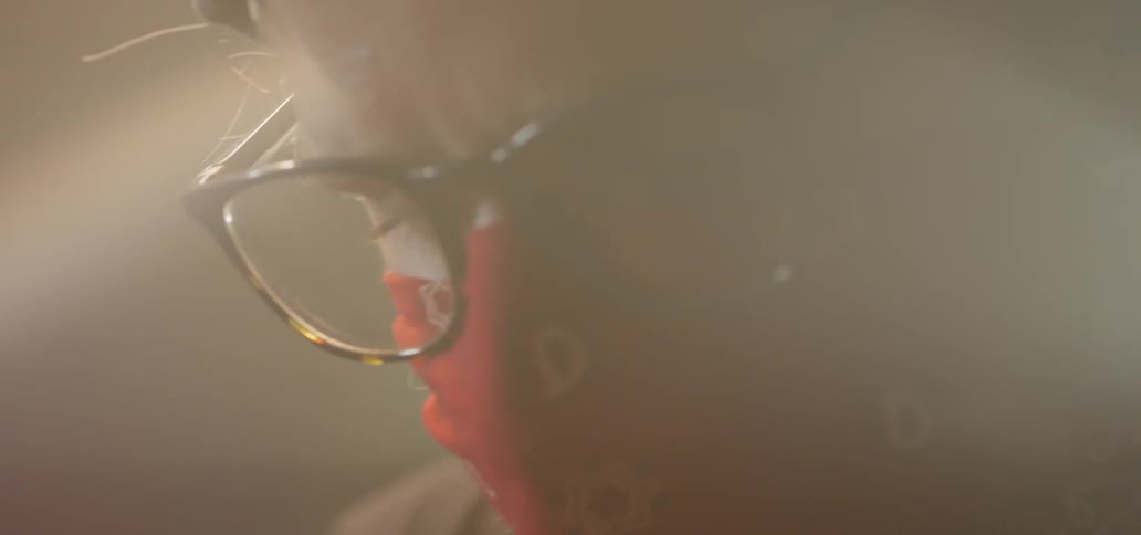 A man wears glasses and a handkerchief over his mouth to protect himself from the sparks