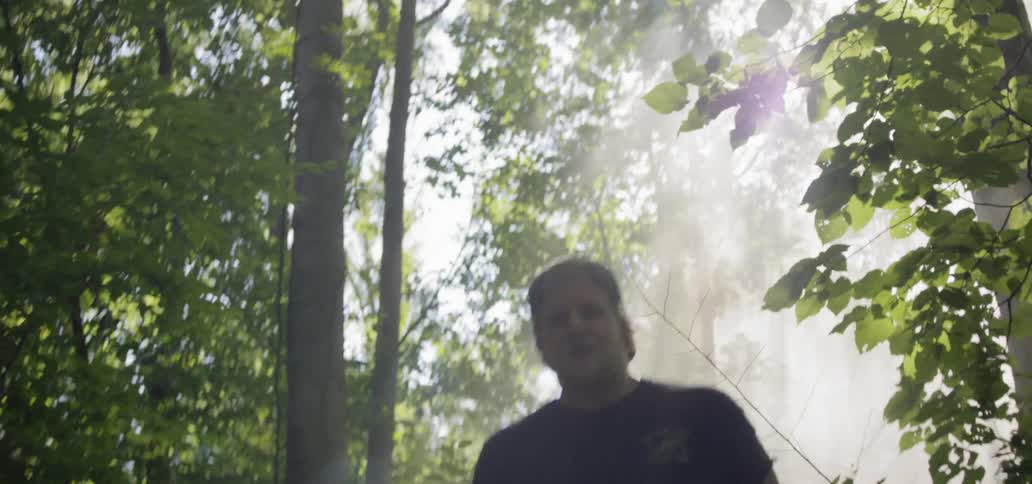 A man with a knife runs through a forest