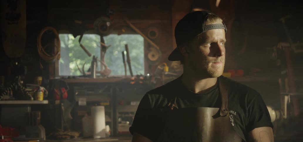 A man wears a leather apron while standing in a workshop