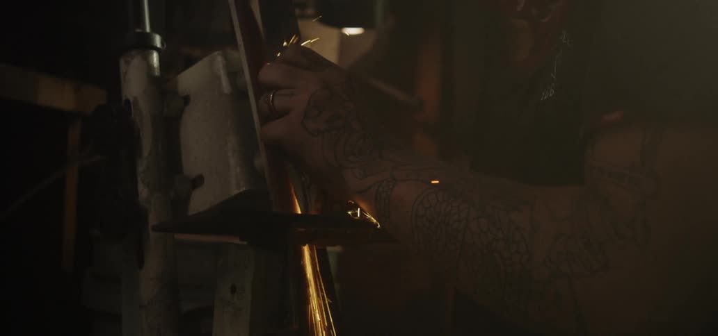 A man holding a piece of metal to a machine causing sparks to fly