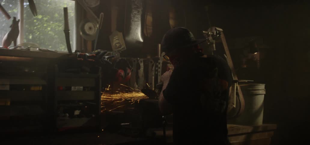 A man uses a welding gun in his garage
