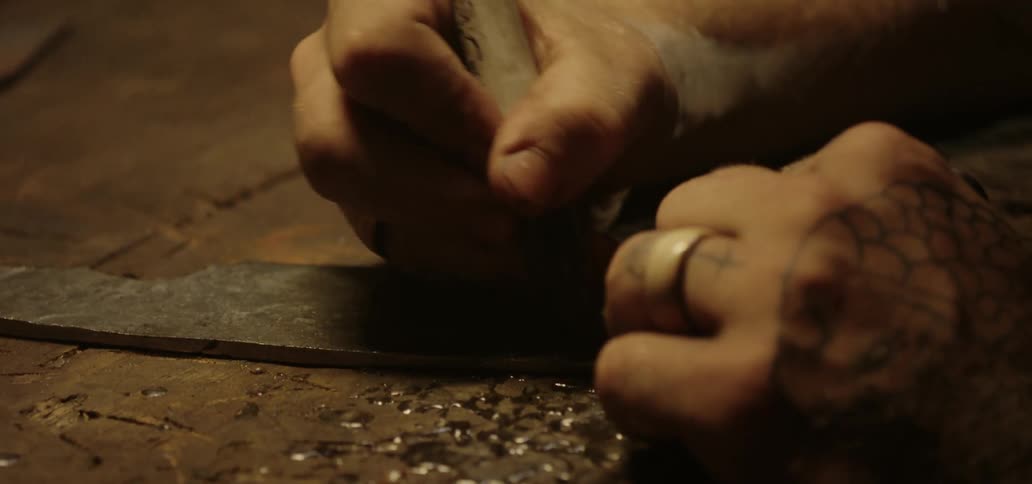 A persons hands with tattoos writing on a piece of metal with a marker