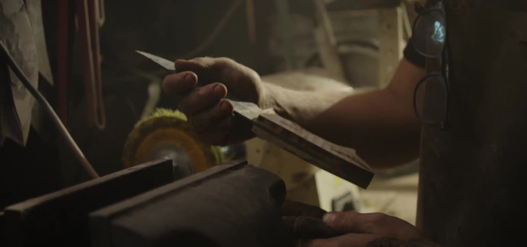 A blacksmith removing a knife from a vice before examining it