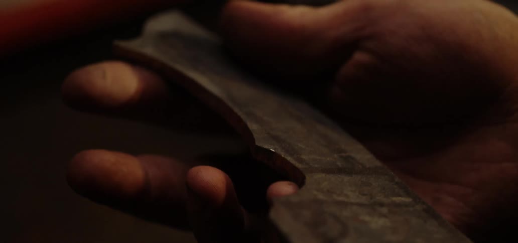 A man is examining a knife blank in his hand
