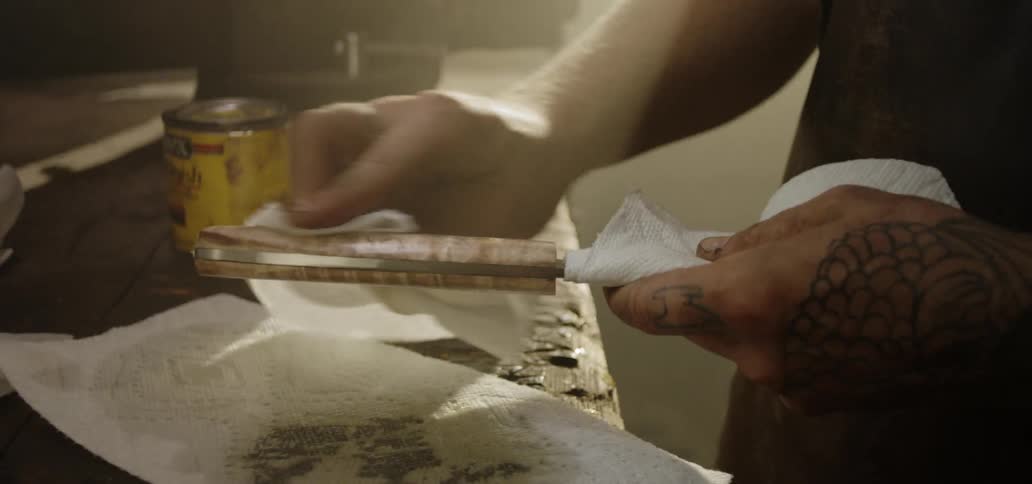 A man rubs the handle of a knife with a paper towel