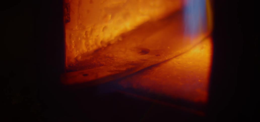 A blue flame heating up a piece of metal in a furnace