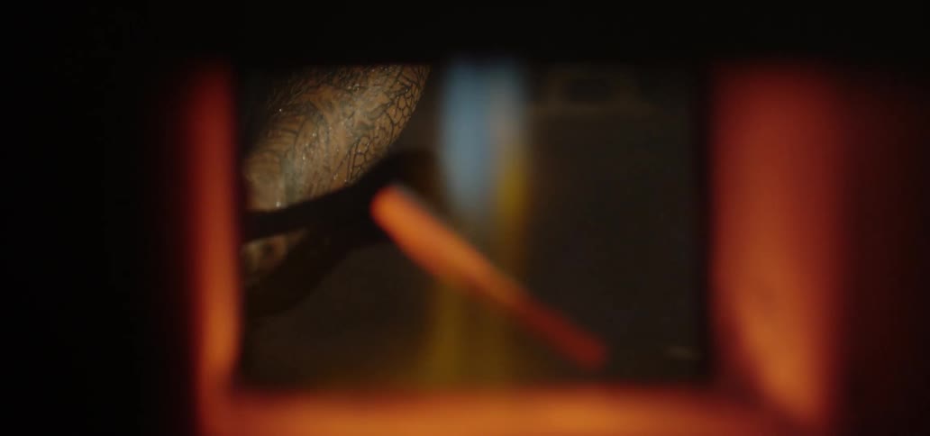 A person places a piece of red hot iron into a flaming kiln