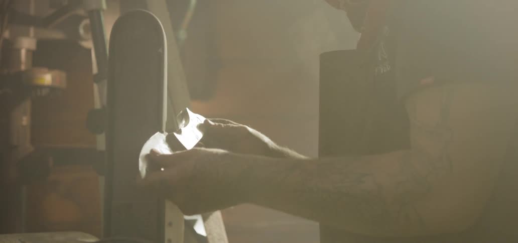 A man examines and then starts to sharpen a knife blade