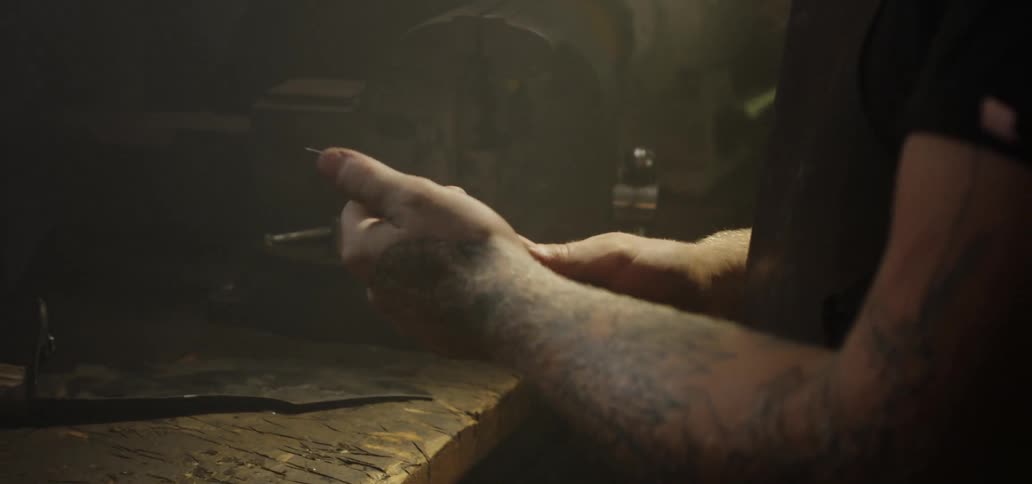 A man tests the sharpness of a knife blade while working in a workshop