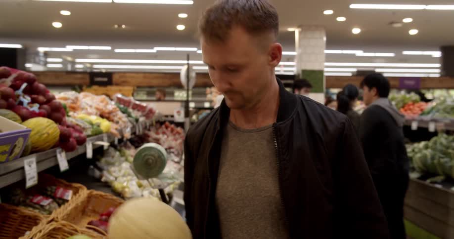 Man selects cantaloupe at grocery store
