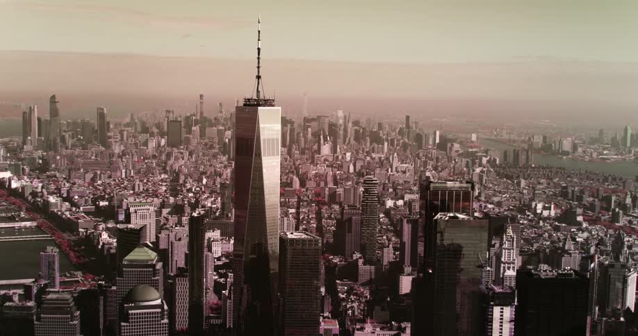 A skyscraper with a spire towers over nearby buildings in an urban area