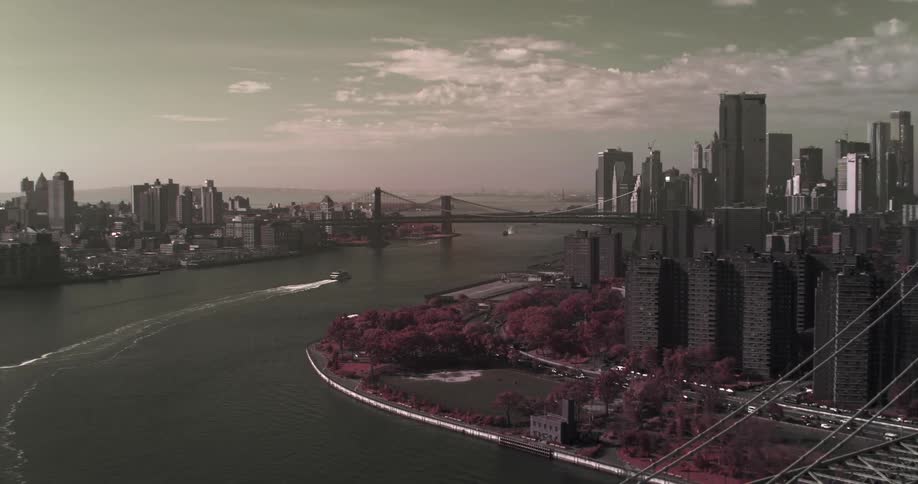 A boat leaves a wake after traveling under the williamsburg bridge and heading toward the brooklyn bridge