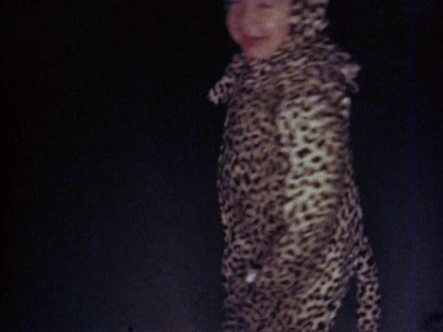 A toddler walks around in a leopard costume