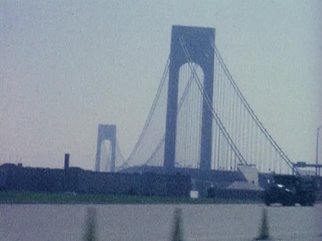Cars and trucks driving in front of a large bridge