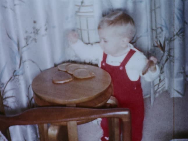 A toddler knocks over a set of coasters on a table