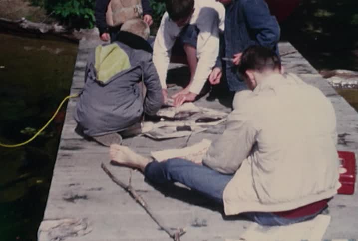 Old footage of kids cleaning fish on a pier