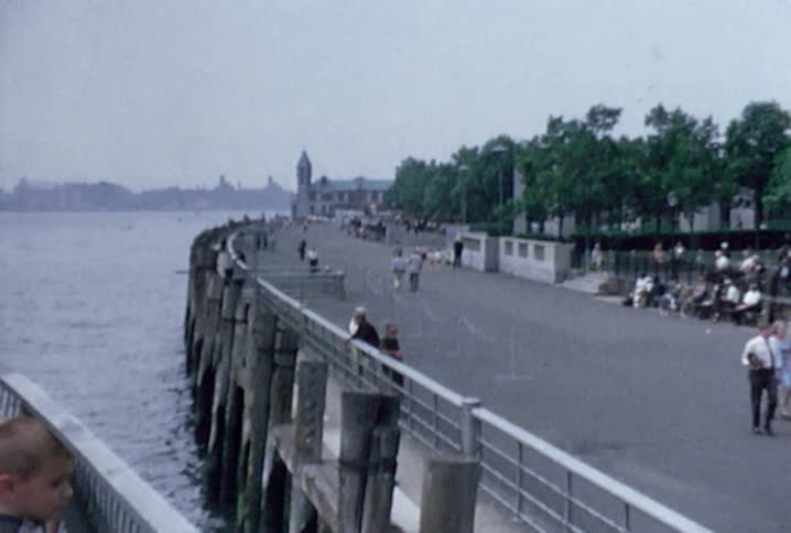 Two children stand on a docked boat looking out at the people below