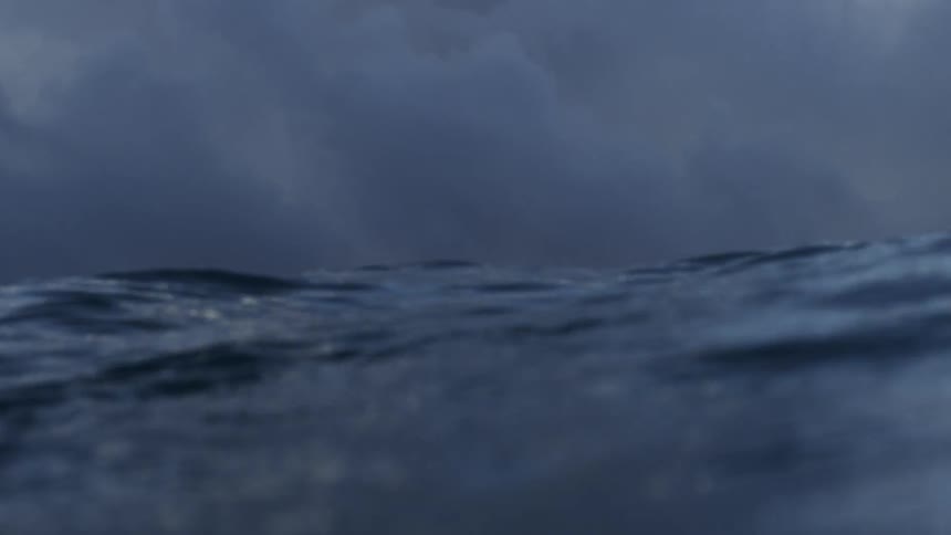 Waves crash with a storm in the distance