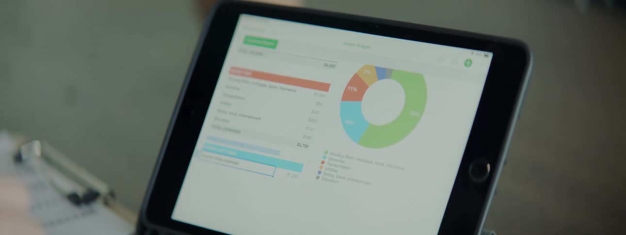 A person scrolls on their tablet while looking at graphs