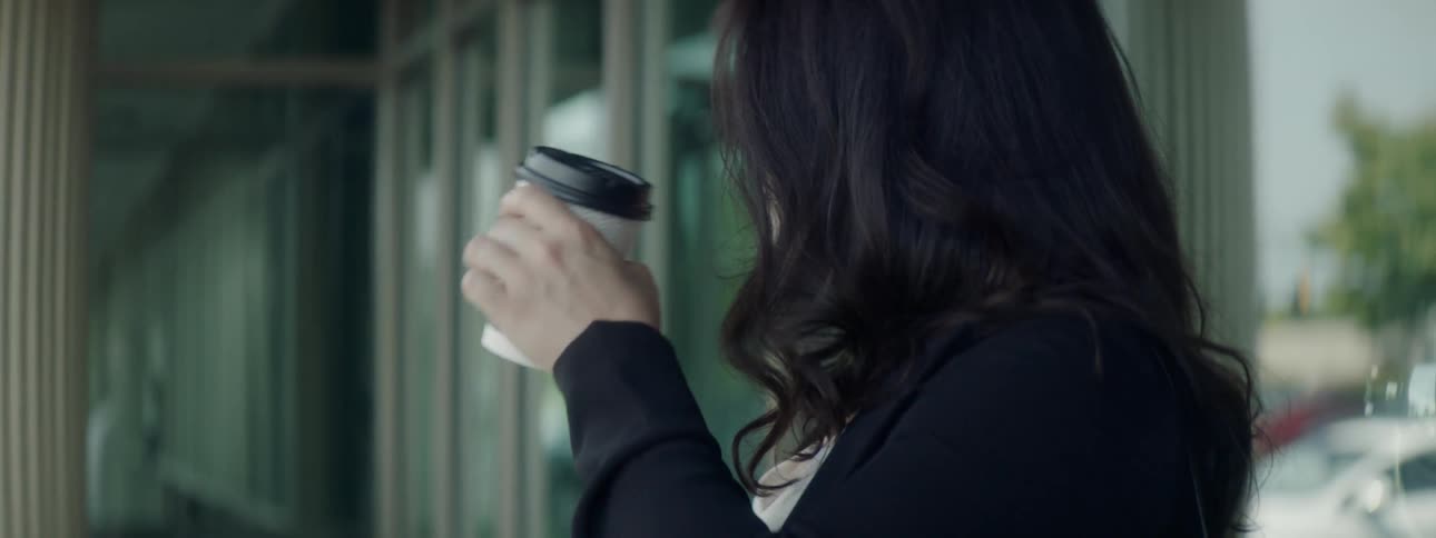 Woman drinks from a take out coffee cup then holds up her cellphone