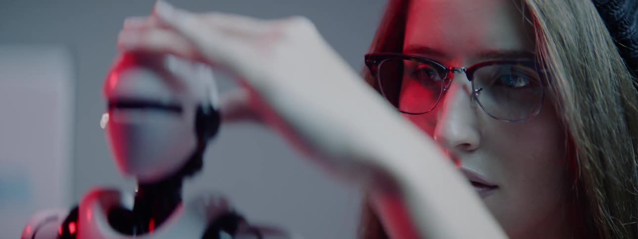 A woman holds a small robot and manipulates its head