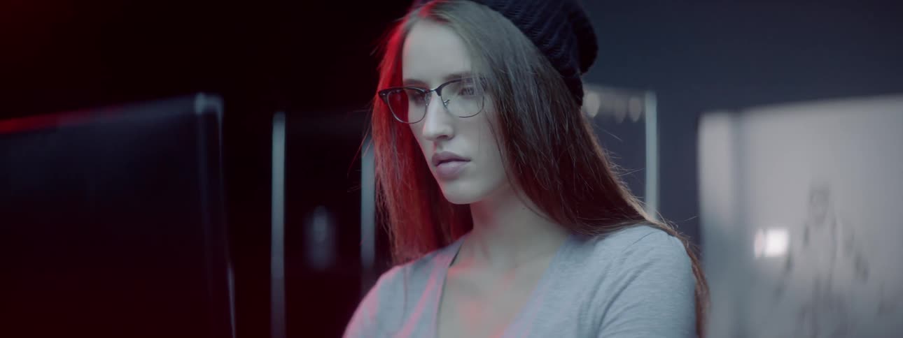 A woman wearing a hat is looking at a monitor